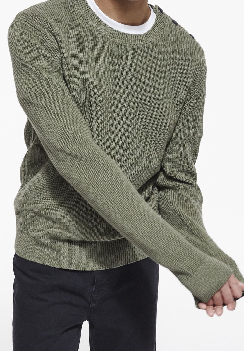 Maglione verde oliva lavorato a maglia con scollo rotondo e texture a costine, con dettagli di bottoni sulla spalla e maniche lunghe.