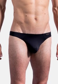 Slip in tessuto nero con texture a coste, vita elasticizzata e copertura minima. Presenta un piccolo etichetta con logo sul lato sinistro anteriore.