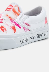 Chaussure blanche en toile sans lacets ornée d'empreintes de rouge à lèvres colorées en rose et orange, avec le texte "LOVE CAN SAVE US" sur le côté.