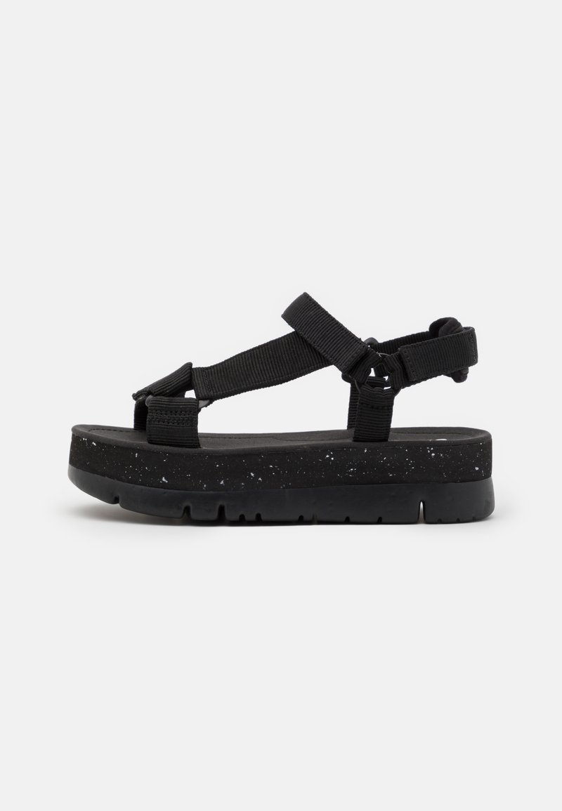 Sandalia de plataforma negra con correas de nylon ajustables, plantilla texturizada y suela de EVA moteada. Presenta un diseño moderno y minimalista.