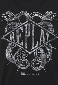 Camiseta de algodón negra con un gran diseño gráfico blanco de dos serpientes rodeando un diamante con el texto "REPLAY" y "SINCE 1981".