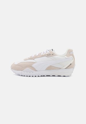 Biało-beżowe buty sportowe Puma z zamszowymi akcentami, białymi sznurówkami, fakturowaną podeszwą i logo Puma na boku oraz języku, pokazane od strony wewnętrznej.
