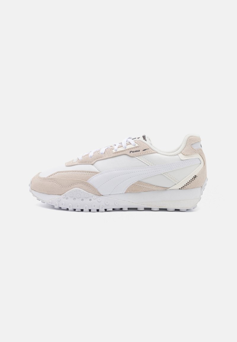 Baskets Puma blanches et beiges avec des touches en daim, lacets blancs, semelle texturée et logo Puma sur le côté et la languette, montrées de la face intérieure.