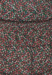 Tela con estampado floral que presenta pequeñas flores rojas y blancas sobre un fondo oscuro. Cintura elástica y textura fruncida. Material suave y ligero.