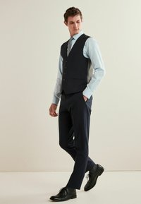 Marine Blaumann mit fünf Knöpfen, hellblauem Hemd, grauen Anzughosen und schwarzen Dressschuhen, die ein formelles Outfit ergeben.