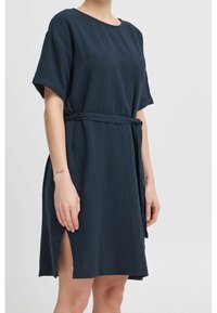 Mörkblå klänning med bälte i strukturerad tyg, med korta ärmar och sidofickor för extra detalj.