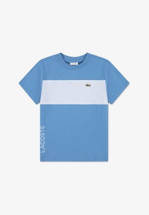 T-shirt bleu à manches courtes avec une bande horizontale blanche, petit logo crocodile vert sur la poitrine et texte "LACOSTE" en bas à gauche.