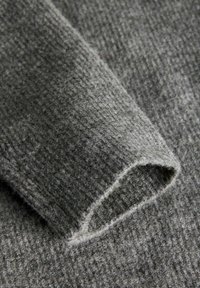 Tessuto a maglia grigio carbone con un motivo testurizzato a coste. Il bordo presenta una finitura morbida e arrotolata per un aspetto informale.