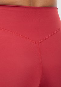 High-waisted red leggings featuring smooth, stretchy fabric with flat seams and a reinforced waistband for support and comfort.