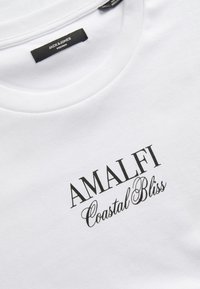 Hvid bomulds t-shirt med sort trykt tekst: "AMALFI Coastal Bliss." Rund halsudskæring og en glat tekstur med en behagelig pasform.