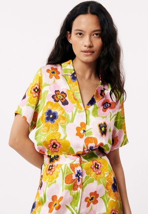 Chemise à manches courtes, à boutons, avec un grand motif floral coloré sur un fond rose clair ; fabriquée dans un tissu léger avec une coupe décontractée.