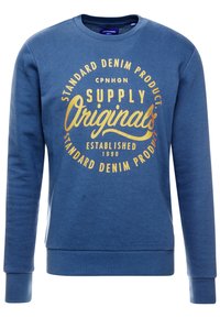 Sudadera de cuello redondo azul, hecha de una tela suave, que presenta una gran impresión gráfica retro multicolor en la parte frontal, con texto y un diseño circular.
