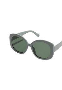 Grå solglasögon med en kraftig, oval ram och mörkgröna linser. Ramen har en slät, matt yta med smala bågar.