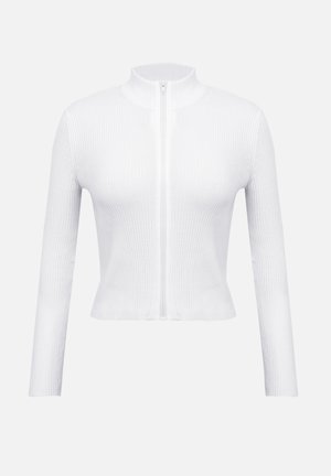 Bela zadrga s črtastim vzorcem, dolgimi rokavi in visokim ovratnikom. Ima osrednjo zadrgo in oprijet kroj, ki poudarja teksturiran material.