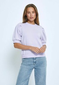 Ljust lila sweatshirt med puffärmar, slät textur, ribbade mudd och nederkant, kombinerad med ljusblå jeans. Enkelt design och passform.