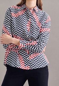 Knapp-up skjorta i marinblå, vit och röd geometrisk zigzag-mönster. Långa ärmar, krage, med en strukturerad passform och vita knappar.