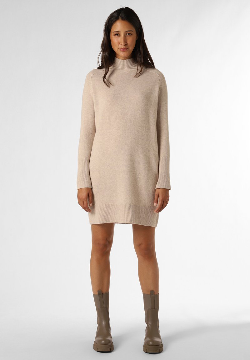 Strick-Turtleneck-Kleid in Hellbeige mit langen Ärmeln und gerippten Bündchen, kombiniert mit braunen Stiefeletten, glatte Textur.