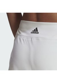 Witte sportshorts van lichtgewicht stof. Heeft een soepele tailleband met een zwart Adidas-logo. Gelaagde stof op de benen met naden.