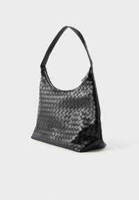 Bolsa de mão preta em tecido trançado com uma silhueta relaxada, apresentando um único cabos curvado e uma textura lisa e brilhante.