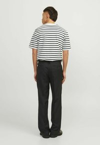 Stripet kortærmet t-shirt i hvid og marineblå, parret med sorte bukser. Sættet har en afslappet pasform og et enkelt design.