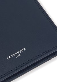 Navy blue leather wallet featuring fine stitching, a smooth texture, and embossed branding "LE TANNEUR 1898" in silver.