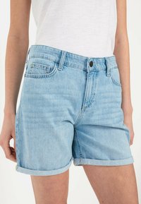 Lichtblauwe denim shorts met opgerolde omslagen, met voorzakken, een knoopsluiting en subtiele vervaging. Gemaakt van katoen.