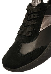 Black sneaker featuring a mix of suede and leather, round laces, textured surface, and a rubber sole with a patterned tread.