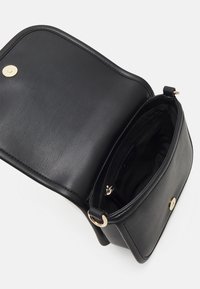 Borsa a tracolla in pelle nera con forma arrotondata, chiusura a scatto dorata e una piccola tasca interna con zip. Texture esterna liscia.