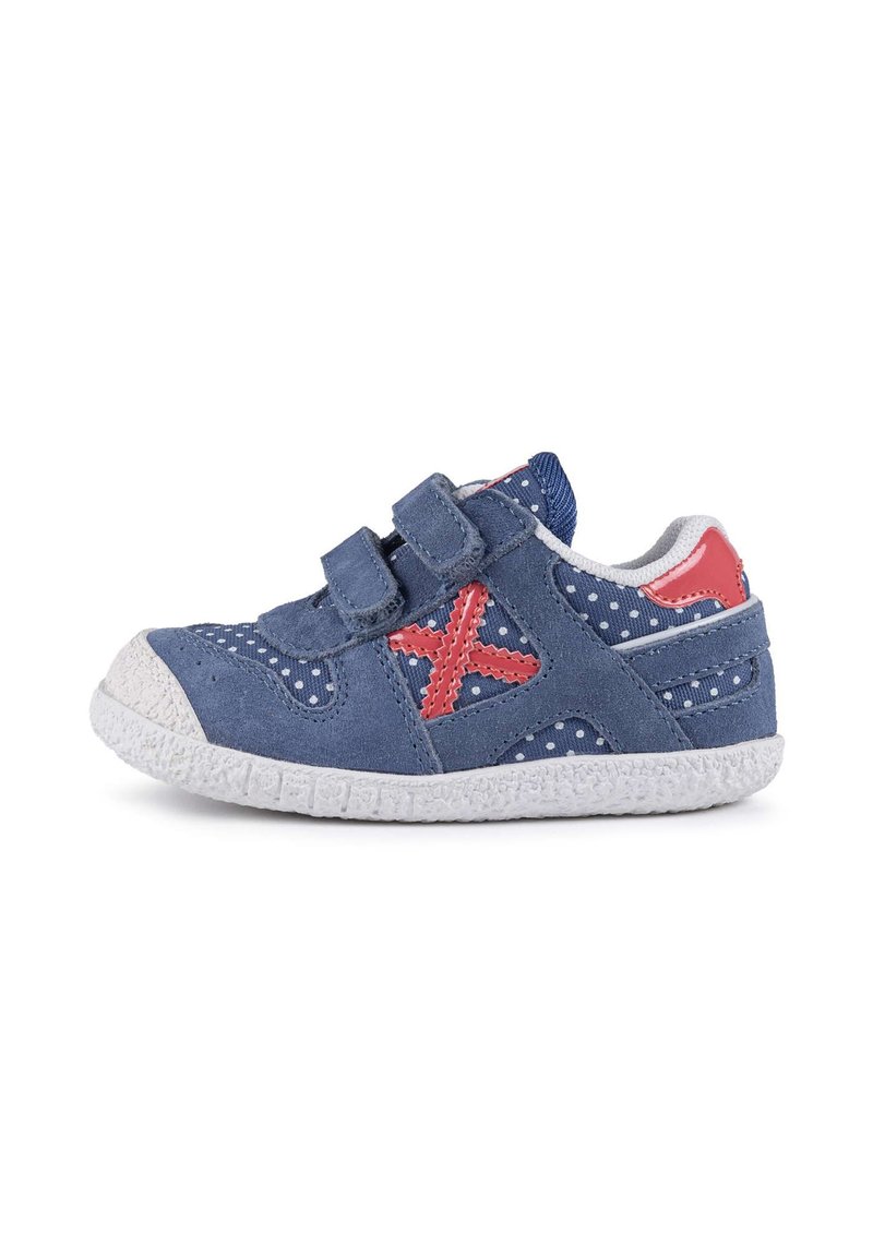 Chaussures en suède bleu avec des pois blancs, des accents roses et deux sangles Velcro. Semelle extérieure en caoutchouc blanc avec une texture antidérapante. Design à bout arrondi.