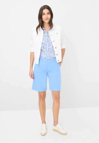 Witte denim jacket, gebloemde blouse in blauw en roze, en lichtblauwe shorts. Casual sneakers. Gladde stof, getailleerde pasvorm en eenvoudig ontwerp.