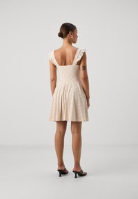 Cream-colored dress with short ruffled sleeves, a square back, and a flared skirt featuring decorative eyelet details.