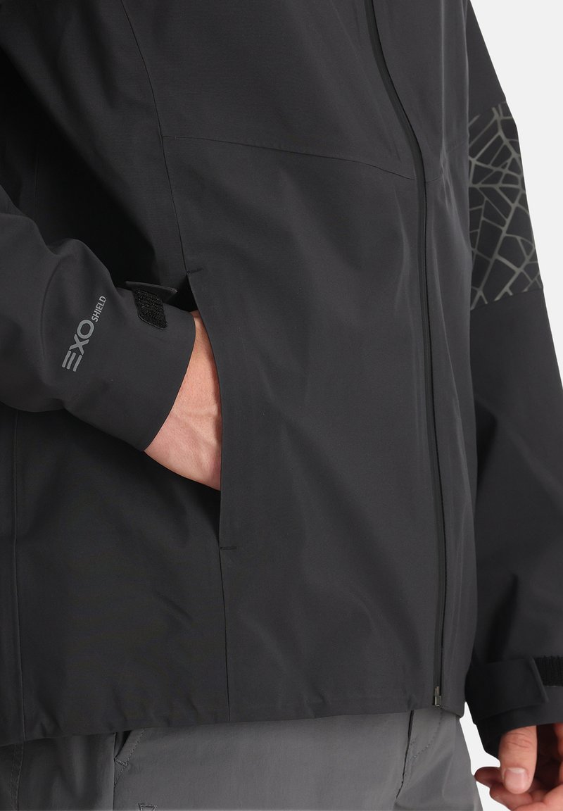 Czarna wodoodporna kurtka z zamkiem błyskawicznym, teksturowanymi akcentami na ramionach, regulowanymi mankietami i boczną kieszenią. Posiada logo "EXO SHIELD".