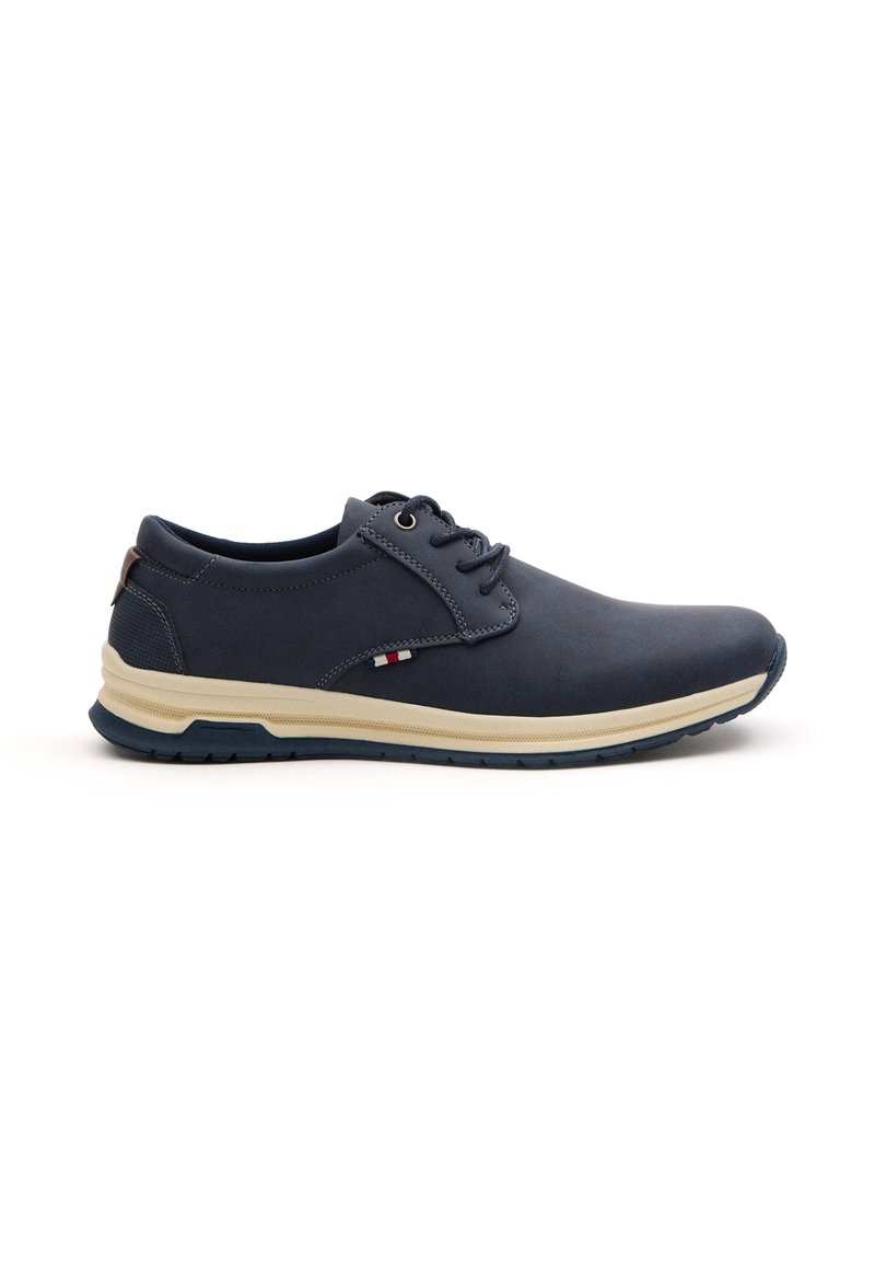 Zapato de cuero azul marino con punta redondeada, diseño de cordones, media suela color crema y acentos texturizados cerca del talón. Suela de goma para agarre.