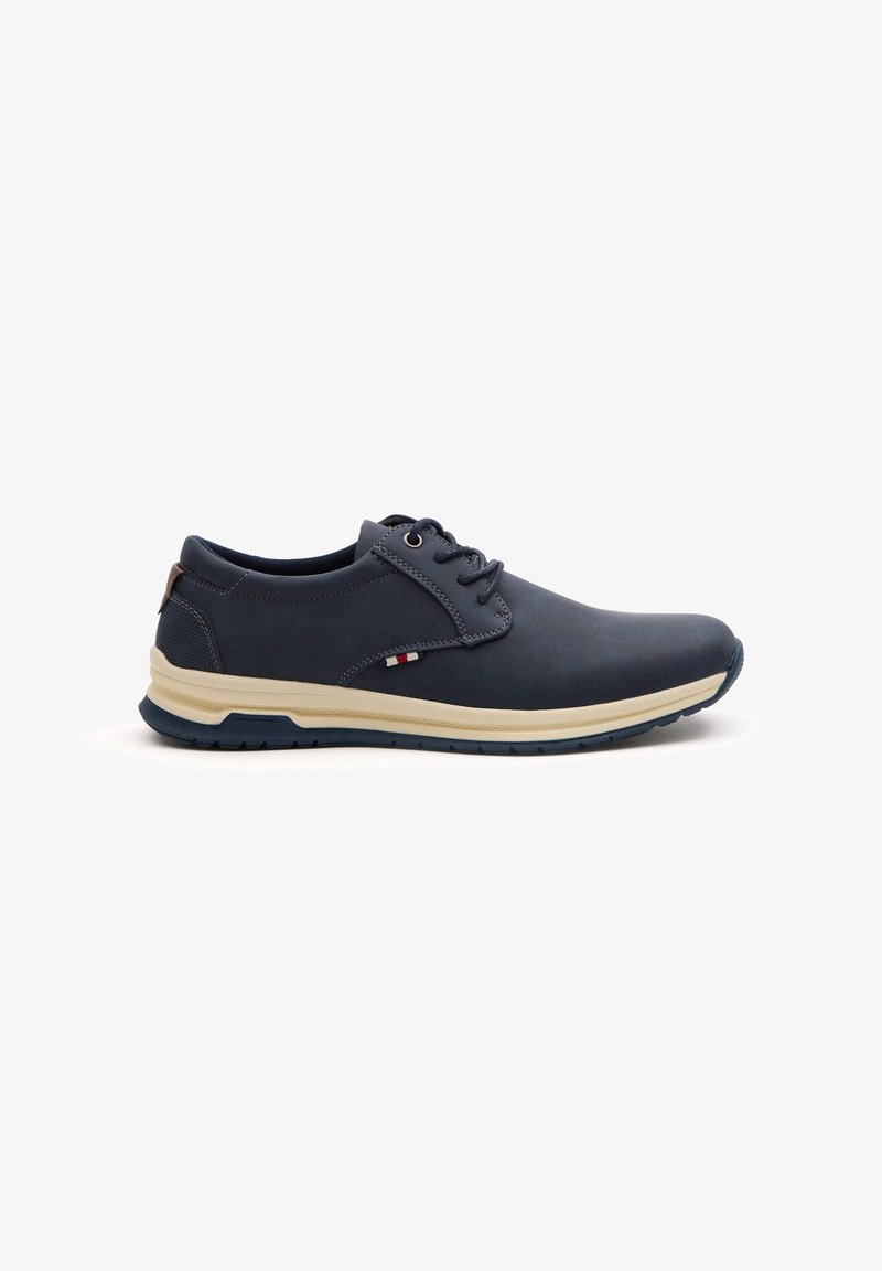 Zapato de cuero azul marino con punta redondeada, diseño de cordones, media suela color crema y acentos texturizados cerca del talón. Suela de goma para agarre.