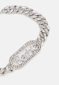 Silver chain necklace features thick links accentuated with clear rhinestones. A rectangular pendant with "Barbie" is embedded within rhinestones.