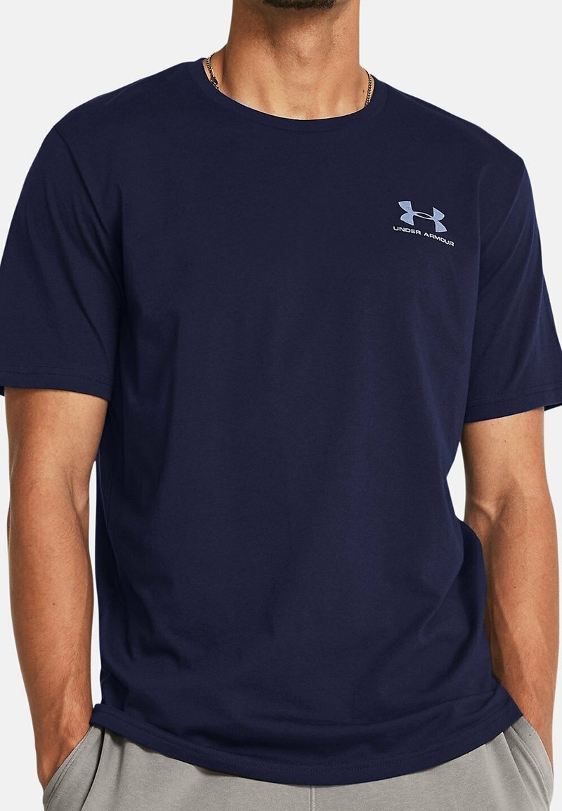 Mörkblå bomullströja med rund hals, korta ärmar och en diskret ljusgrå Under Armour-logga på vänster bröst.