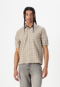 Camicia a maniche corte a quadri nei toni beige e crema, con chiusura a bottoni, taschino sul petto e un design a vestibilità comoda.
