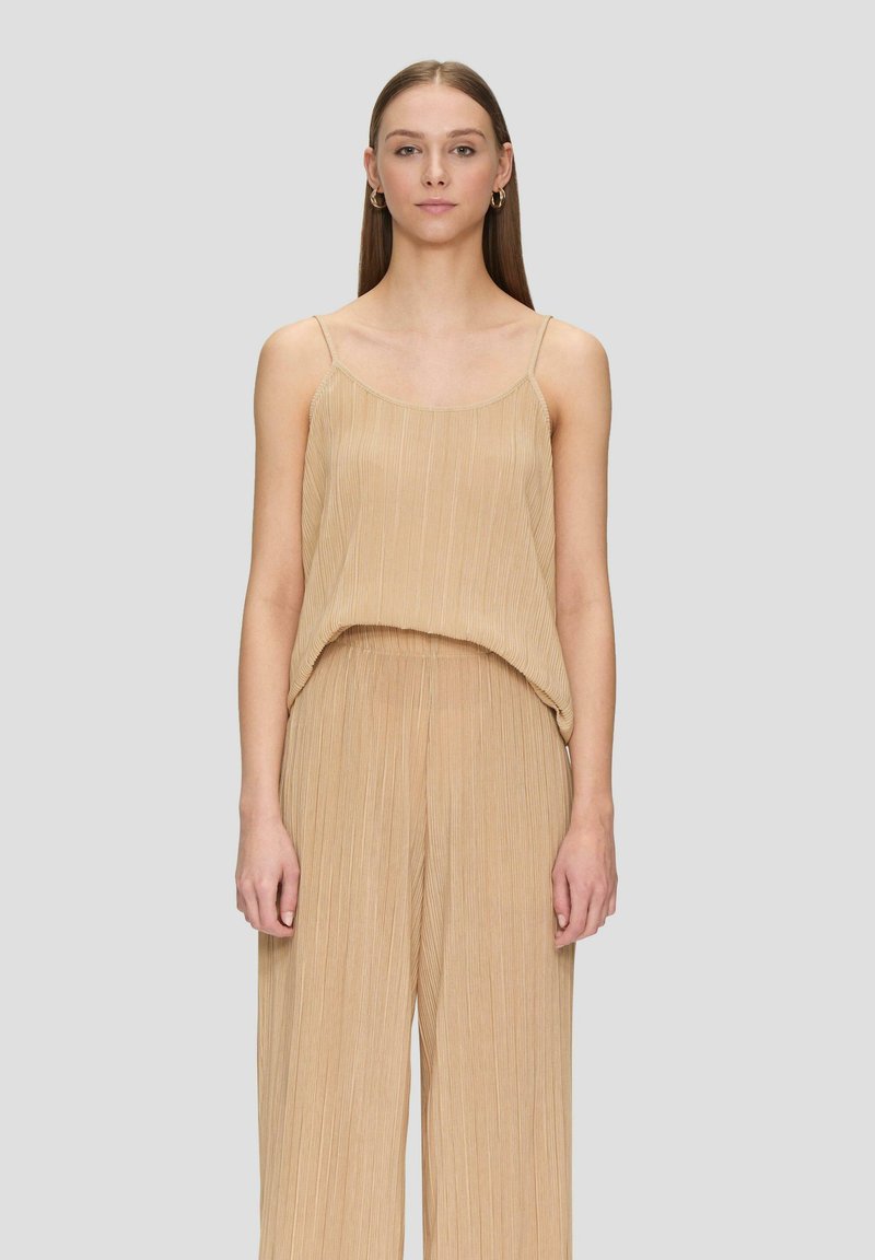 Beige geplooide mouwloze top met een ontspannen pasvorm, delicate bandjes en een zachte textuur. Gepaard met bijpassende losse broek.