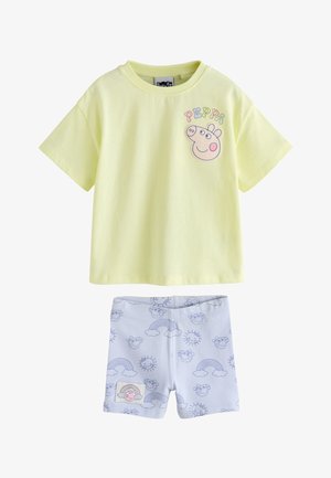 Żółta koszulka z krótkim rękawem z twarzą Peppy Pig i napisem, w połączeniu z białymi szortami z wzorem tęczy, słońc i twarzy Peppy Pig.