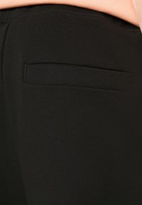 Černé bavlněné legíny s malou zadní kapsou. Hladký povrch a pružný materiál, ideální pro pohodlí a flexibilitu v nošení.