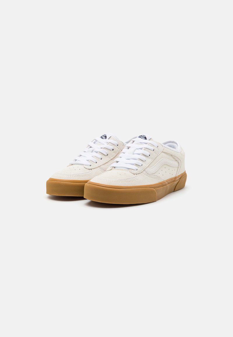 Weiße Wildleder-Low-Top-Sneaker mit einer Gummisohle, ausgestattet mit weißen Schnürsenkeln und einem Logetikette auf der Zunge. Perforierte Seitendetails.