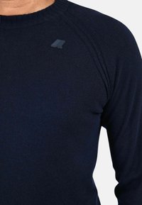 Maglione lavorato a maglia blu navy con scollatura a girocollo, polsini a coste e finitura testurizzata. Presenta un piccolo dettaglio del logo sulla spalla sinistra.