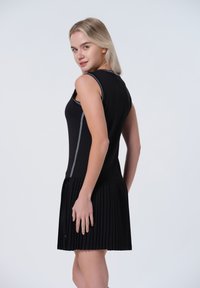 Robe noire sans manches avec un corsage ajusté et une jupe plissée, ornée de coutures grises sur les côtés et d'une texture lisse.