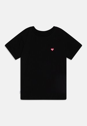 T-shirt noir à manches courtes avec un petit logo cœur rouge sur la poitrine gauche affichant "MAKIA CO" sur fond blanc.