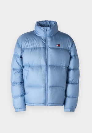 Gaiši zila pūkaina jaka ar augstu apkakli, ar rāvējslēdzēju un kviltotu tekstūru. Uz kreisā krūškurvja ir mazs logos.