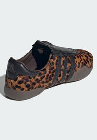 Tenisky s leopardím vzorom a čiernym koženým popruhom, s textúrovaným zvrškom, okrúhlym krytom šnúrok a gumovou podrážkou.