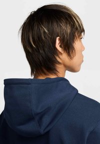 Felpa blu navy con una texture morbida, dotata di cappuccio con cordoncino e design minimalista. Dettagli di cucitura visibili sul colletto.