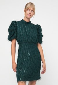 Teal dress with a textured, fuzzy fabric, puffed sleeves, sequins, and a high neckline. Short length with a fitted waist.