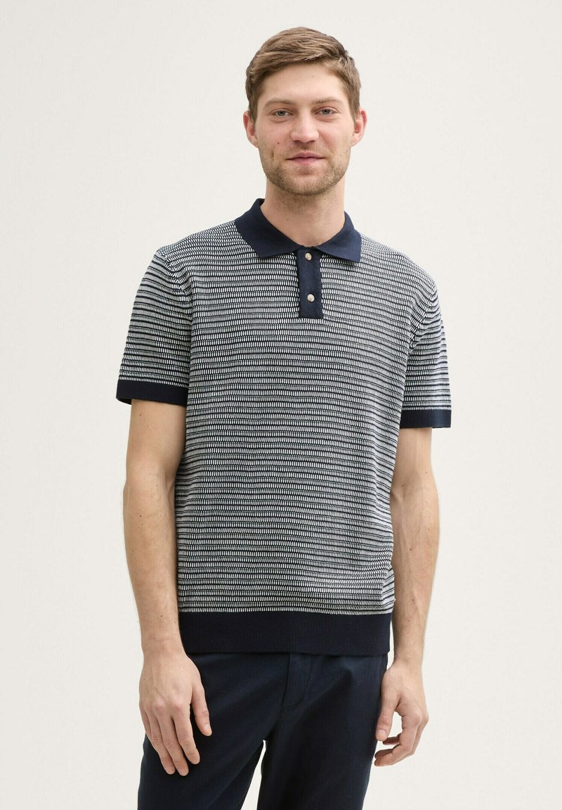 Polo à manches courtes rayé bleu marine et blanc avec un col bleu marine, patte de boutonnage à deux boutons, poignets côtelés et tissu tricoté texturé.
