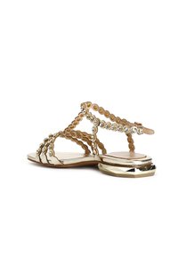 Guld färgad sandal med cirkulära utskärningar, rhinestone detaljer och en tjock klack, med en remdesign och platt sula.